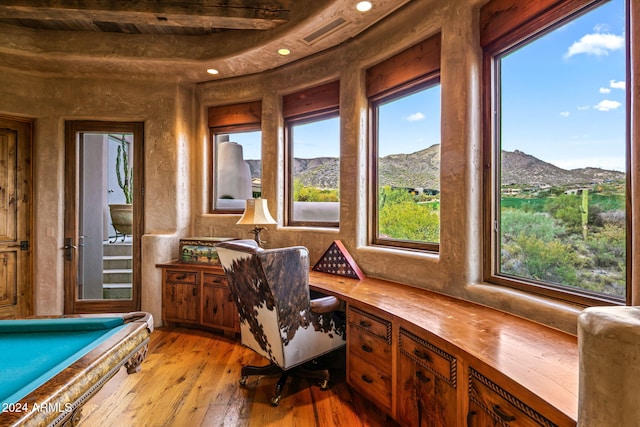 interior space featuring pool table, built in desk, light wood-type flooring, a mountain view, and beam ceiling