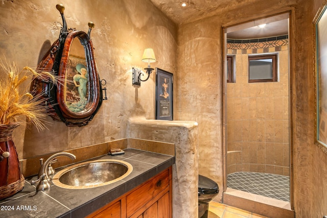 bathroom with vanity, a tile shower, and toilet