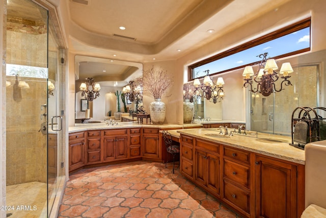 bathroom with an inviting chandelier, vanity, a tray ceiling, and a shower with door