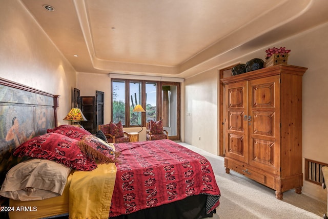 bedroom with light carpet and a tray ceiling