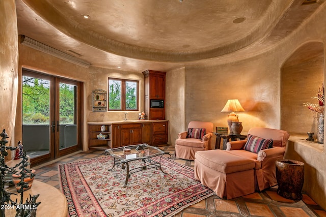 living area with french doors, a tray ceiling, and sink