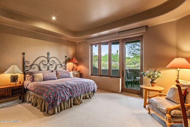 carpeted bedroom featuring access to outside and a raised ceiling