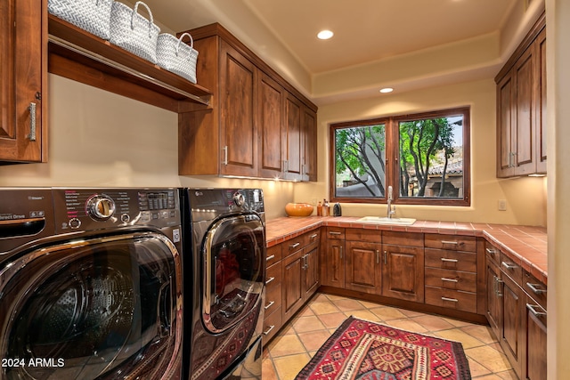 laundry room featuring light tile patterned flooring, cabinets, separate washer and dryer, and sink