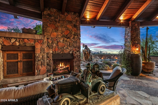 patio terrace at dusk featuring an outdoor stone fireplace