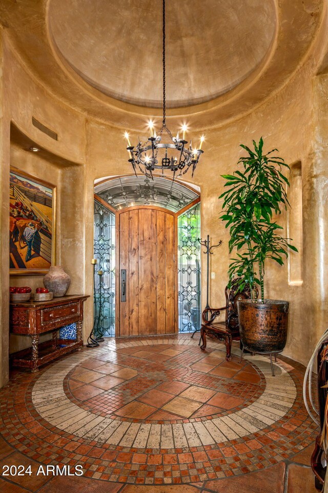 foyer with a raised ceiling, a high ceiling, and a chandelier