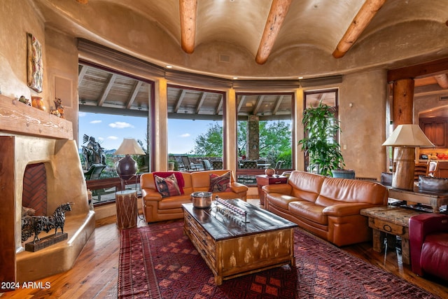 interior space featuring lofted ceiling, a healthy amount of sunlight, hardwood / wood-style floors, and a high end fireplace