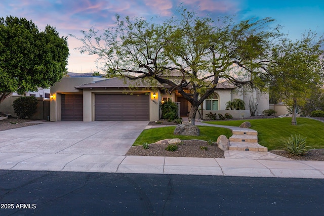 view of front of house with a garage, stucco siding, driveway, and a front lawn