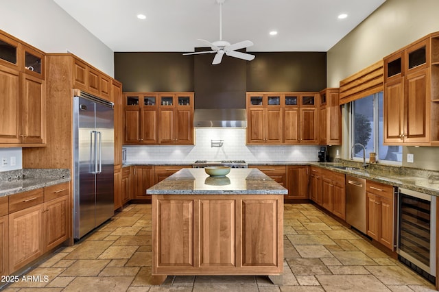 kitchen with stainless steel appliances, stone tile floors, beverage cooler, and a sink