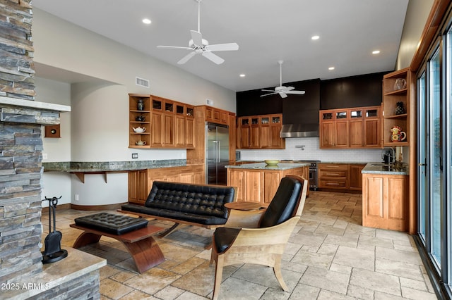 kitchen with high end appliances, open shelves, wall chimney exhaust hood, and stone tile floors