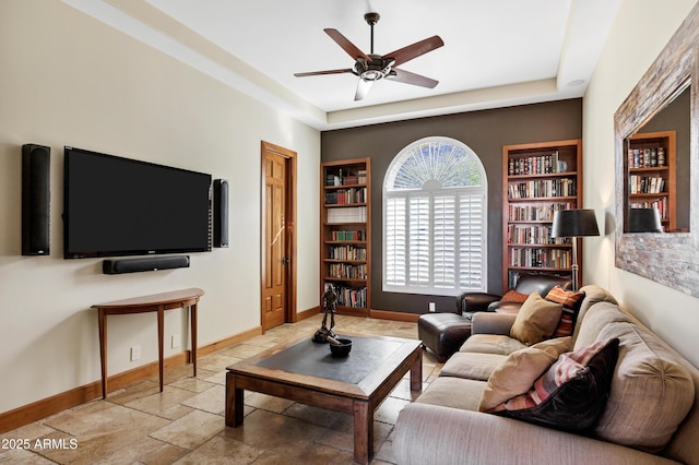 living area with built in features, ceiling fan, baseboards, and stone tile flooring