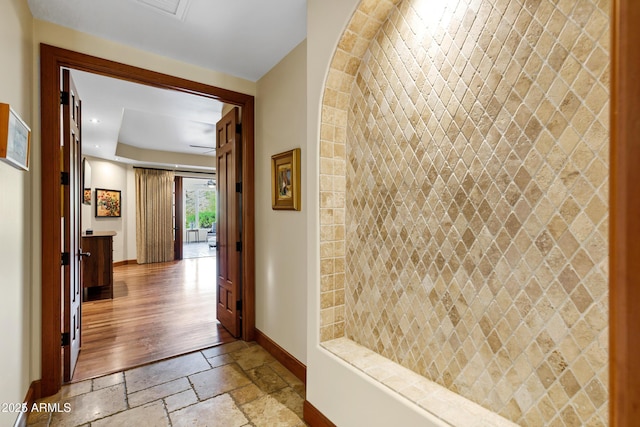 corridor with baseboards, stone tile flooring, and recessed lighting