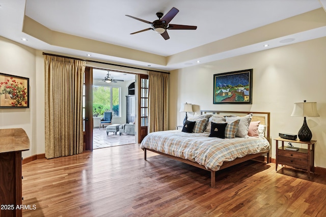 bedroom featuring access to outside, recessed lighting, wood finished floors, a raised ceiling, and baseboards