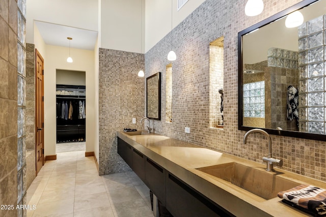 bathroom with a sink, tile walls, tile patterned flooring, and a high ceiling