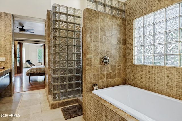 ensuite bathroom featuring tile patterned floors, tiled shower, a ceiling fan, and a wealth of natural light