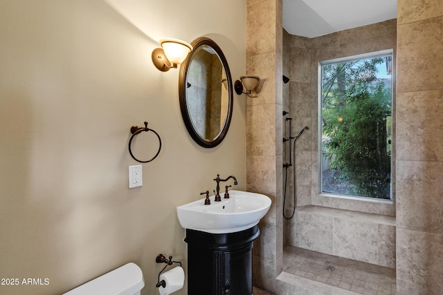 full bath featuring a sink, a tile shower, and toilet