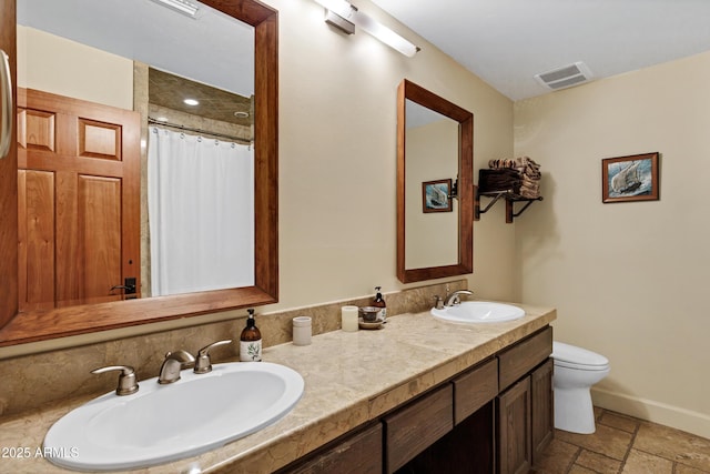 bathroom with a sink, visible vents, baseboards, and stone tile floors