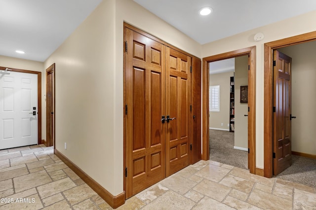 hallway featuring recessed lighting, baseboards, and stone tile flooring