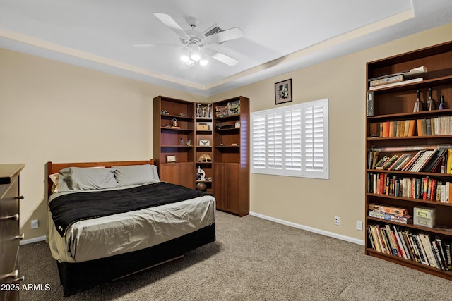 bedroom featuring carpet, a tray ceiling, baseboards, and a ceiling fan