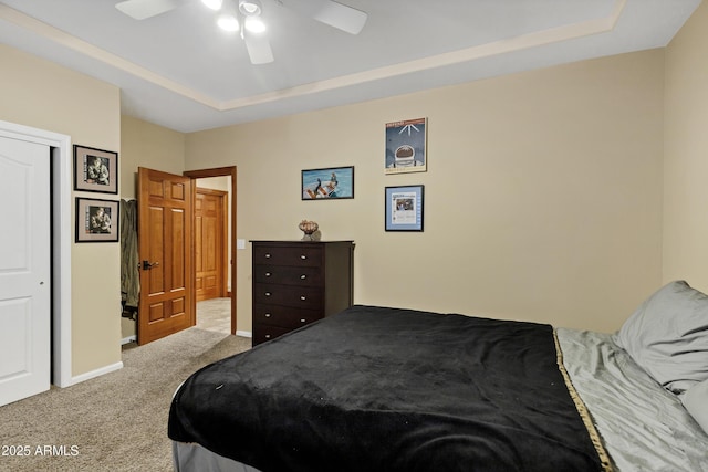 carpeted bedroom featuring a tray ceiling, baseboards, and a ceiling fan