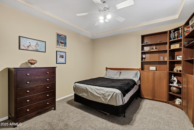 carpeted bedroom with a raised ceiling, ceiling fan, and baseboards