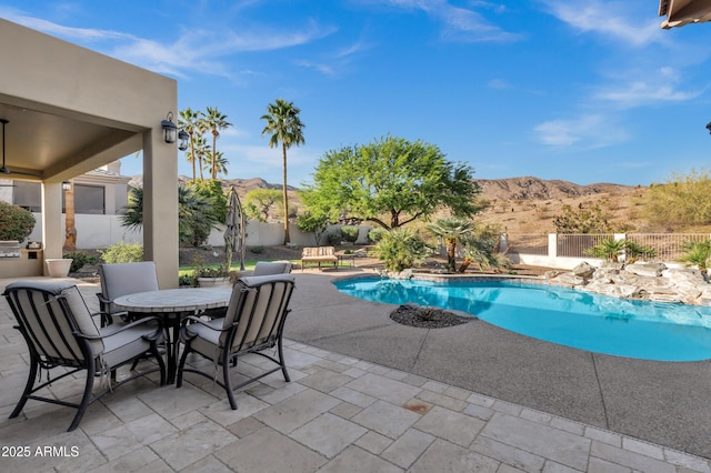 view of pool with a patio area, a mountain view, outdoor dining space, and a fenced backyard