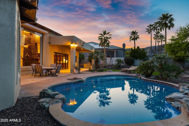 pool at dusk with a patio, a fenced in pool, and fence