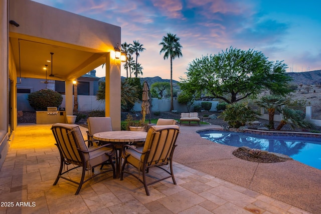 view of patio / terrace featuring outdoor dining space, exterior kitchen, a fenced in pool, a mountain view, and fence