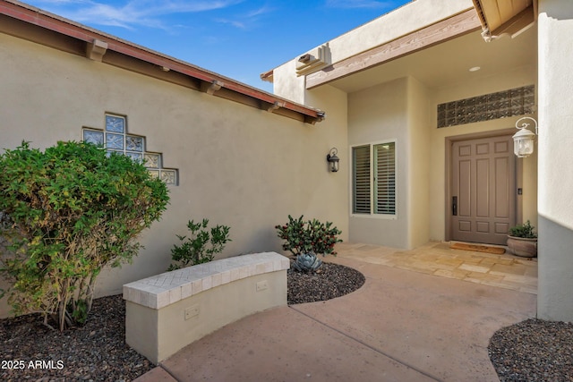 view of exterior entry featuring a patio and stucco siding
