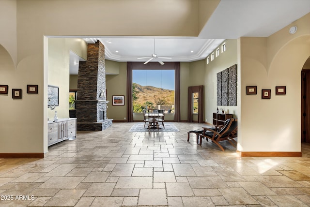 interior space featuring baseboards, a ceiling fan, arched walkways, and a high ceiling
