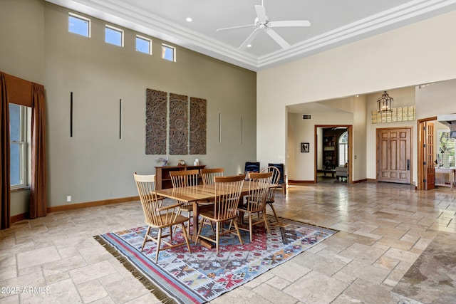 dining area featuring stone tile flooring, baseboards, ceiling fan, and a high ceiling