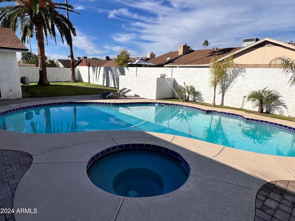 view of pool with a lawn and an in ground hot tub