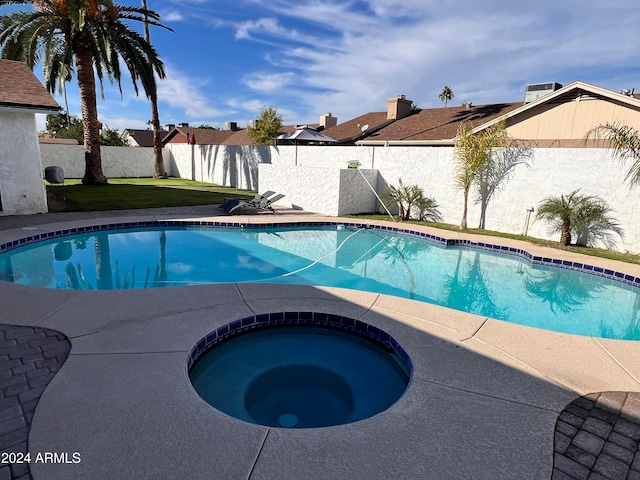 view of pool with a lawn and an in ground hot tub