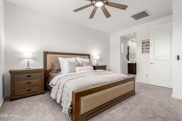 bedroom featuring visible vents, ensuite bathroom, baseboards, light colored carpet, and ceiling fan