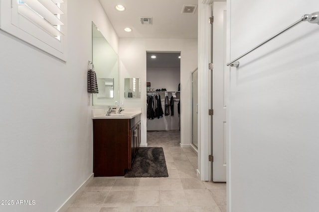 full bathroom featuring vanity, a walk in closet, recessed lighting, and visible vents