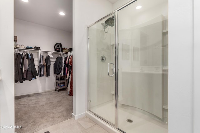 bathroom with a shower stall, a spacious closet, and tile patterned floors