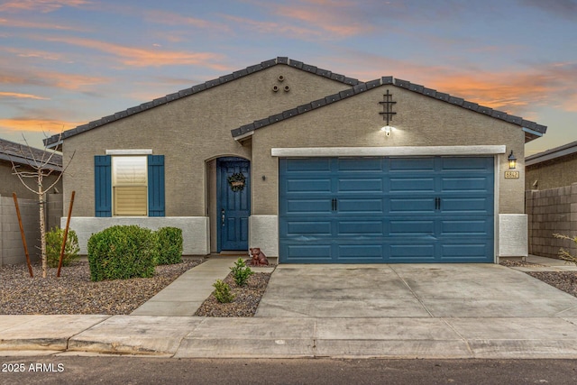 ranch-style house featuring fence, a tile roof, stucco siding, driveway, and an attached garage