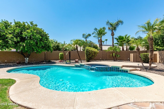 view of swimming pool featuring a pool with connected hot tub and a fenced backyard