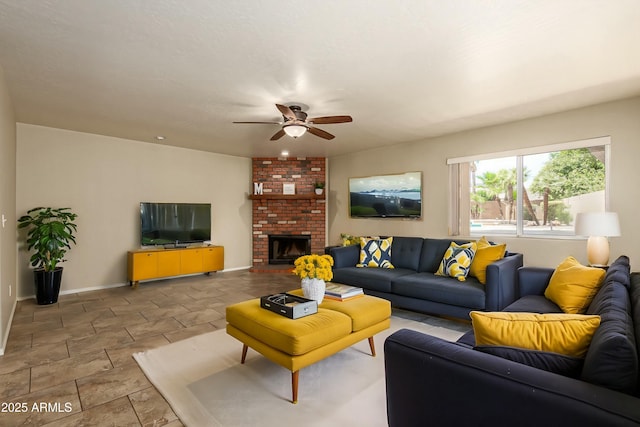 living room with a ceiling fan, a brick fireplace, and baseboards