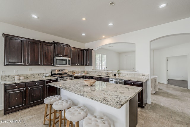 4067 S White Dr, Chandler, AZ 85249 - kitchen with appliances with stainless steel finishes, arched walkways, a sink, a kitchen bar, and a center island
