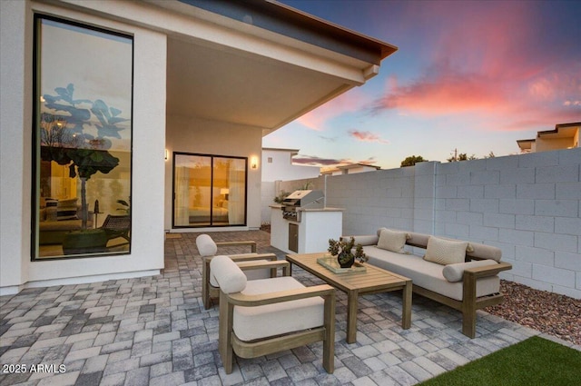 patio terrace at dusk with an outdoor kitchen, area for grilling, and an outdoor hangout area