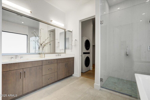 bathroom featuring a shower with door, vanity, and stacked washer / drying machine