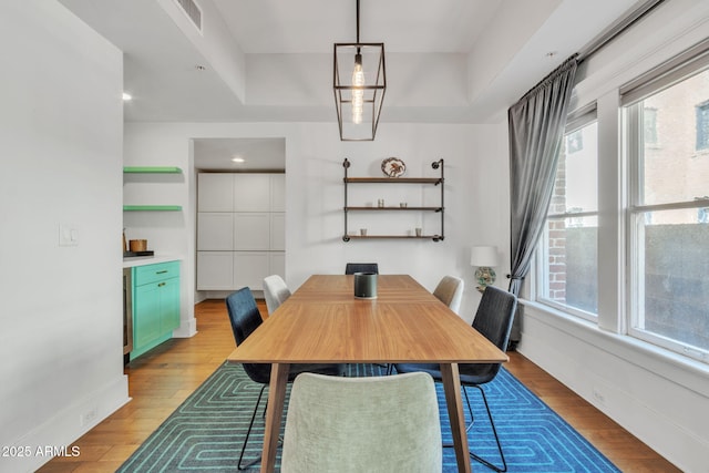 dining room with light wood finished floors, visible vents, and baseboards