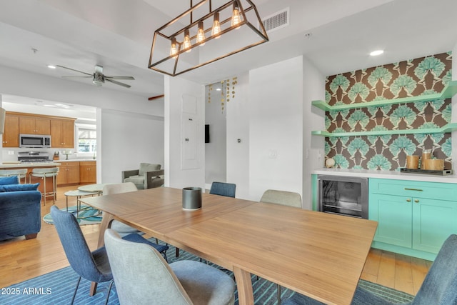 dining room with light wood-style floors, beverage cooler, visible vents, and ceiling fan