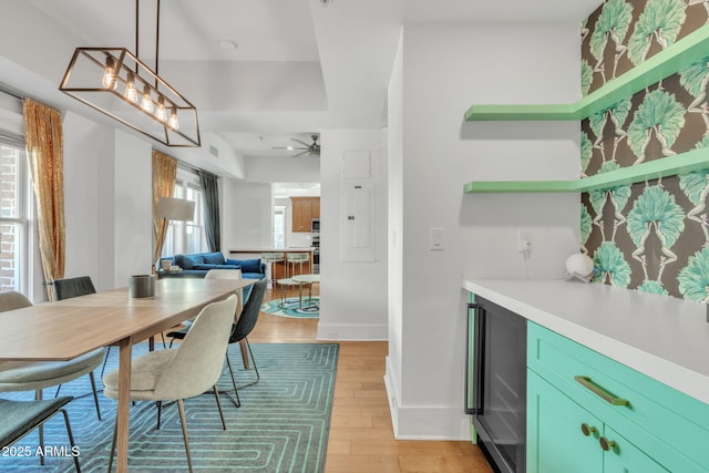 dining room featuring light wood-style flooring, wine cooler, baseboards, and ceiling fan