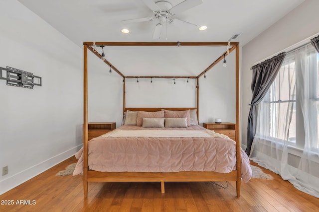 bedroom with light wood-type flooring, multiple windows, and baseboards