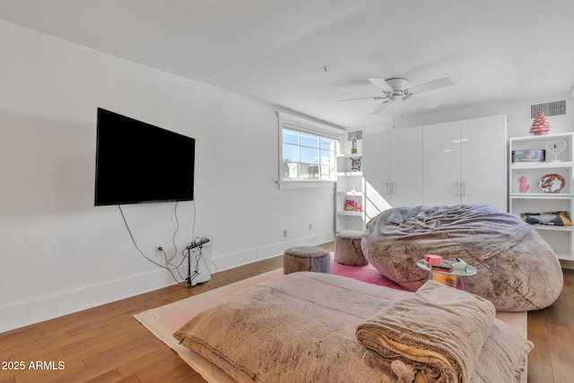 bedroom with a ceiling fan, wood finished floors, visible vents, and baseboards