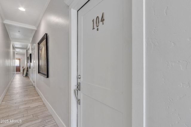 hall featuring ornamental molding, light wood-style flooring, and baseboards