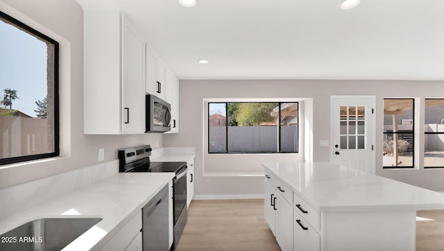 kitchen with stainless steel appliances, recessed lighting, light wood-style flooring, white cabinets, and light stone countertops