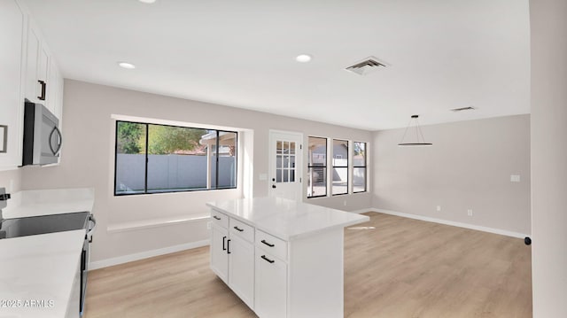 kitchen with visible vents, baseboards, white cabinets, light wood-type flooring, and a center island