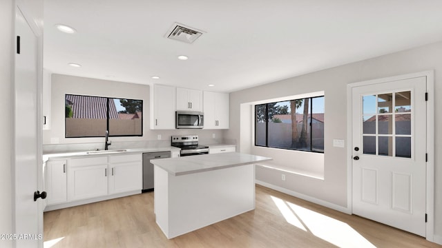 kitchen featuring stainless steel appliances, light countertops, visible vents, light wood-style flooring, and a sink